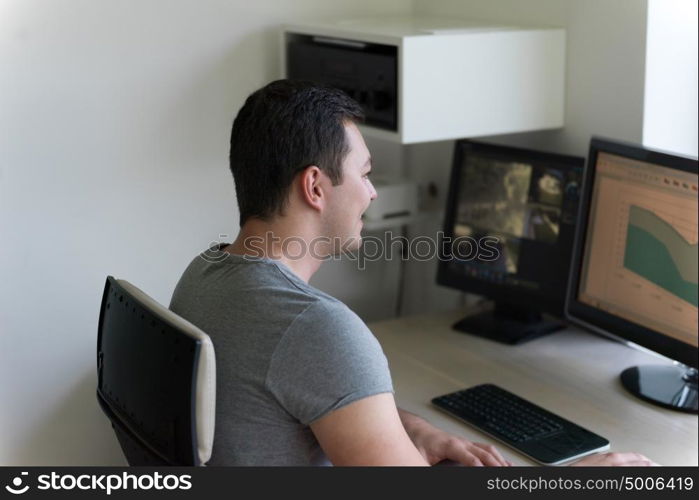 portrait of security system operator looking at CCTV footage at desk in office
