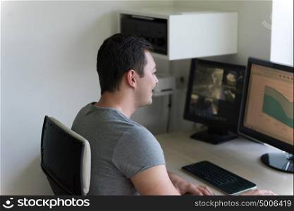 portrait of security system operator looking at CCTV footage at desk in office