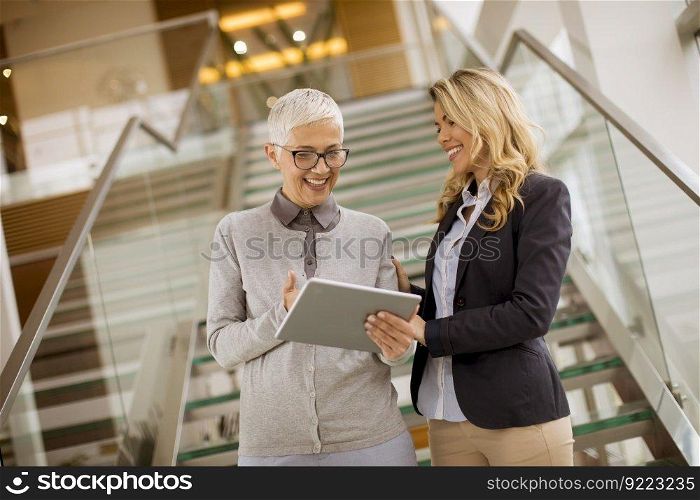 Portrait of senior and young businesswomen  looking at digital tablet  in office