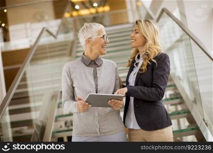 Portrait of senior and young businesswomen  looking at digital tablet  in office