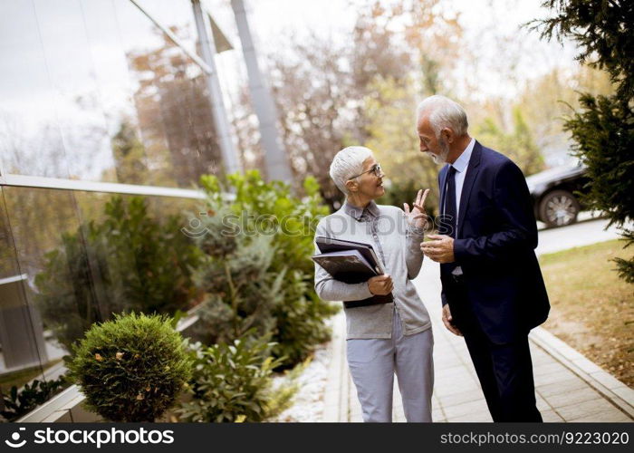 Portrait of senior business people talking outdoors and discussing a document outdoor