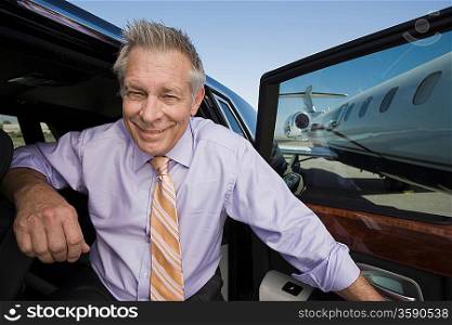 Portrait of senior businessman in front of car.