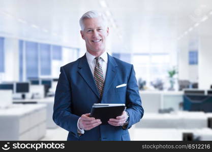 Portrait of senior businessman in front of his modern office with tablet. Senior businessman in his office