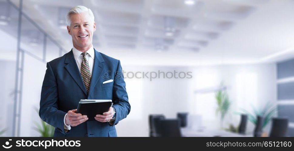 Portrait of senior businessman using tablet in front of his modern office. Senior businessman in his office