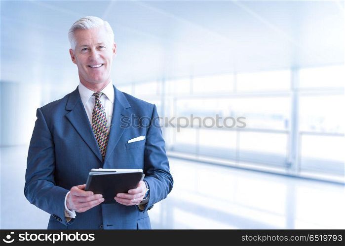 Portrait of senior businessman using tablet in front of his modern office. Senior businessman in his office