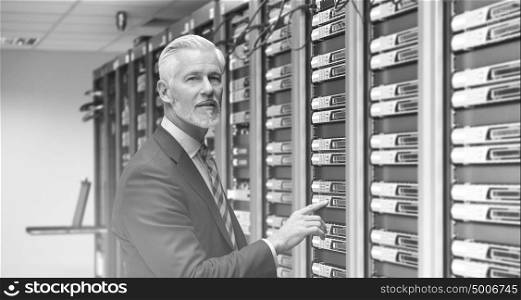 Portrait of senior businessman working in big rack server room