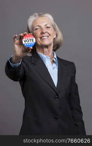 Portrait of senior businesswoman holding voter c&aign pin