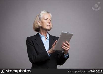 Portrait of senior businesswoman using digital tablet in studio