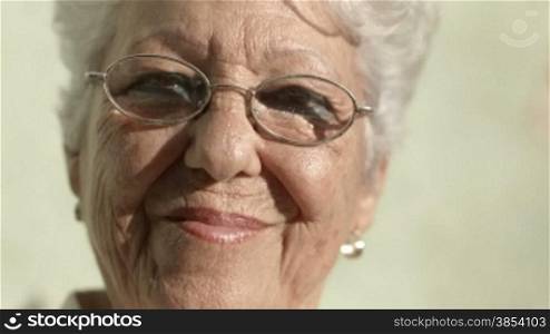 Portrait of senior caucasian woman with glasses looking at camera and smiling. Close-up