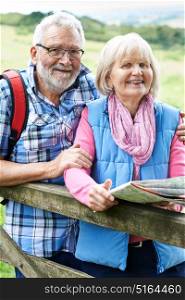 Portrait Of Senior Couple Hiking In Countryside With Map