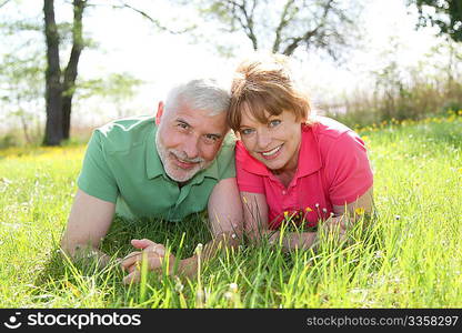 Portrait of senior couple laying in grass