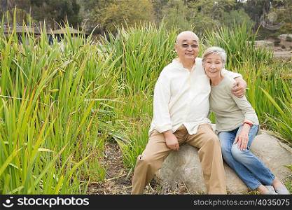 Portrait of senior couple sitting on rock