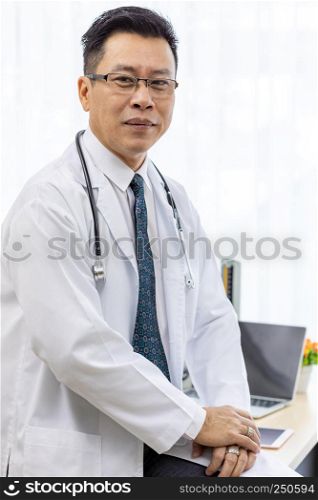 Portrait of senior Doctor in examination room medical office.