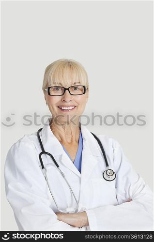Portrait of senior female doctor with arms crossed over gray background
