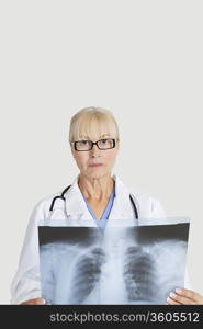 Portrait of senior female doctor with x-ray over gray background