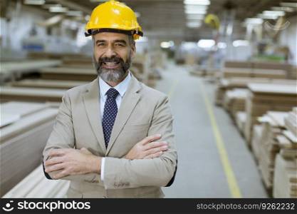 Portrait of senior handsome businessman in suit with helmet in a warehouse