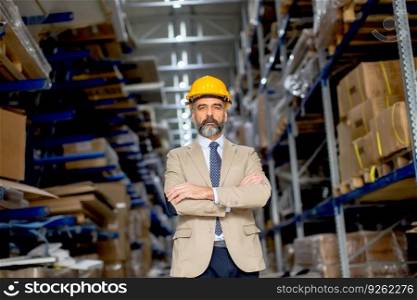 Portrait of senior handsome businessman in suit with helmet in a warehouse