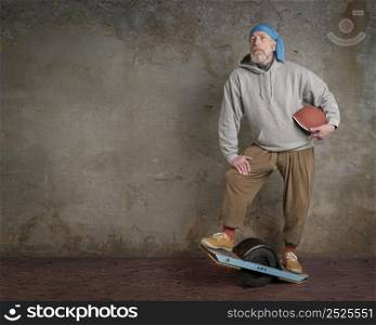 portrait of senior male with one-wheeled electric skateboard in a grunge urban environment
