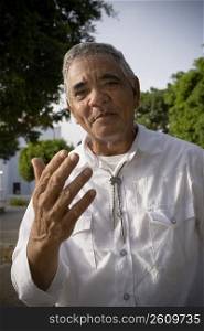 Portrait of senior man gesturing with hands, outdoors