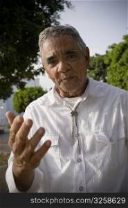 Portrait of senior man gesturing with hands, outdoors