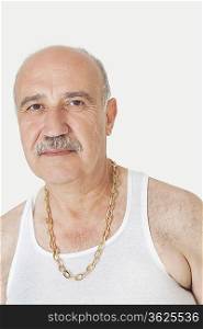 Portrait of senior man in vest with gold chain over gray background