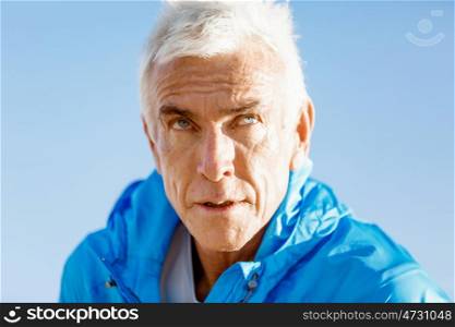 Portrait of senior man outside in sports wear. Man standing outdoors in sports wear looking fit and happy