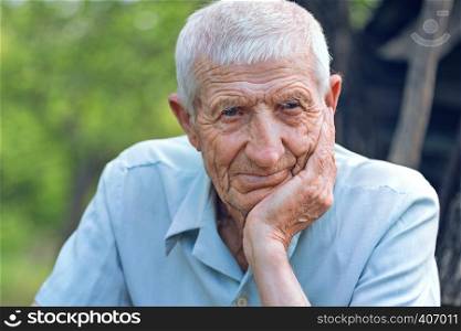 portrait of senior man sits in the garden and looks at the camera