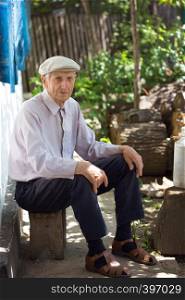 portrait of senior man sitting near his house in the village