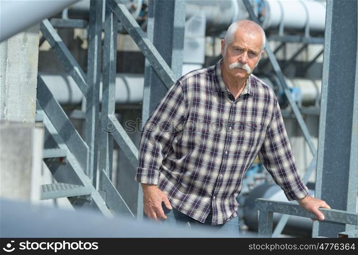 portrait of senior man standing by metal staircase