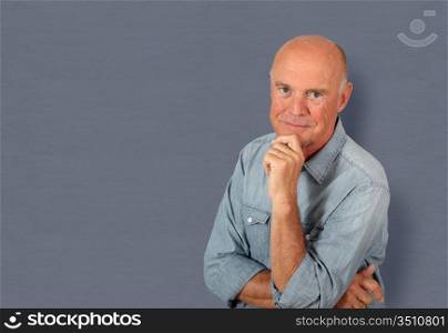 Portrait of senior man standing on grey background