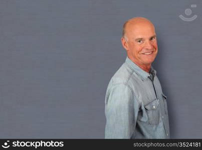 Portrait of senior man standing on grey background