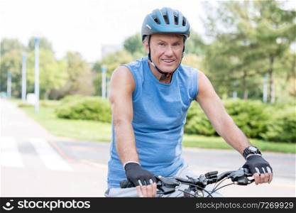 Portrait of senior man wearing helmet while riding bicycle in park