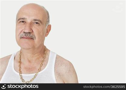 Portrait of senior man with gold chain over gray background