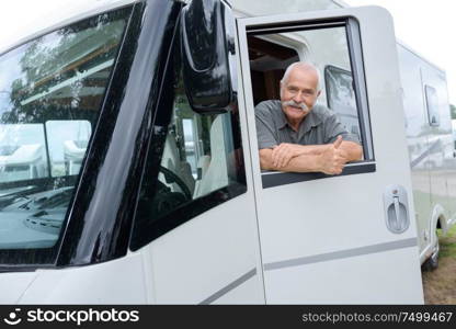 portrait of senior man with motorhome holding thumbs up