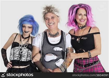 Portrait of senior man with punk females over gray background