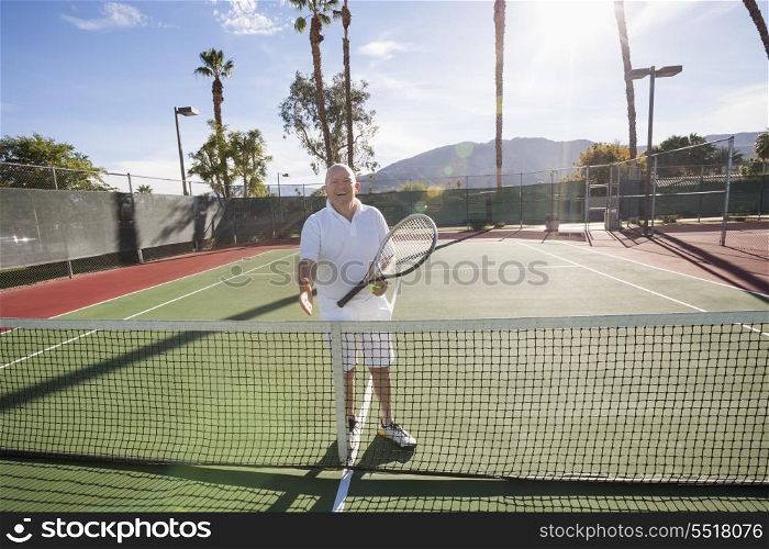 Portrait of senior tennis player offering handshake on court