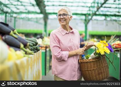 Portrait of senior woman holding basket with bouquet of flowers on market