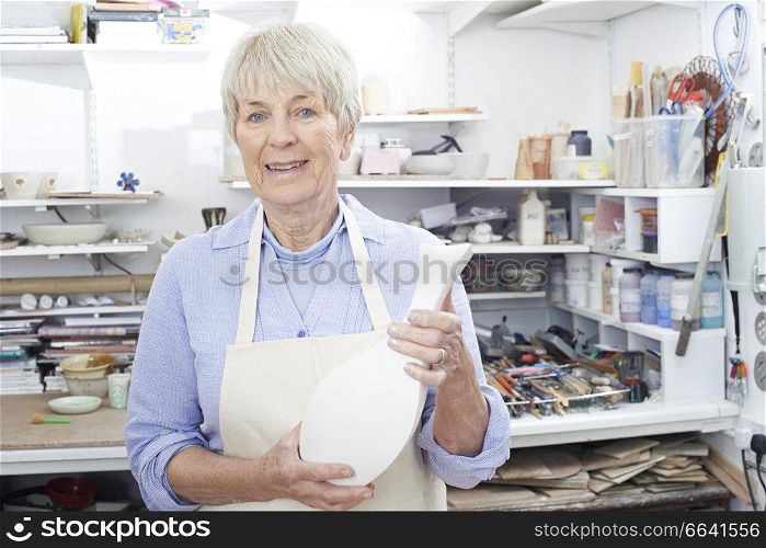 Portrait Of Senior Woman Holding Vase In Pottery Studio