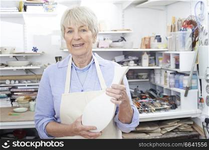 Portrait Of Senior Woman Holding Vase In Pottery Studio