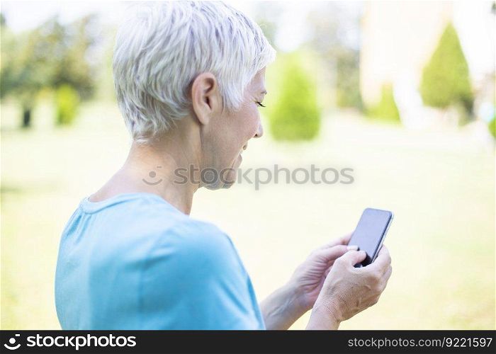 Portrait of senior woman in sports clothing  using smart phone outdoor