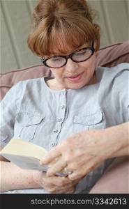 Portrait of senior woman reading book in sofa