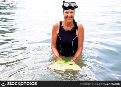 Portrait of senior woman snorkeler holding flippers in sea