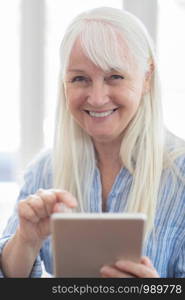 Portrait Of Senior Woman Using Digital Tablet At Home