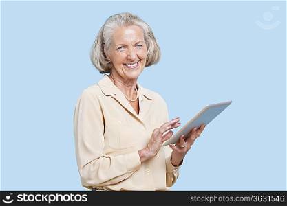 Portrait of senior woman using tablet PC against blue background