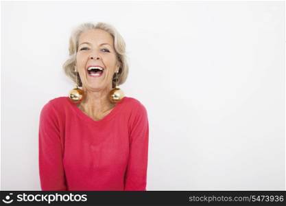 Portrait of senior woman wearing Christmas ornaments over white background