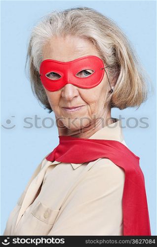 Portrait of senior woman wearing superhero costume against blue background