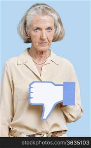 Portrait of senior woman with fake dislike button against blue background