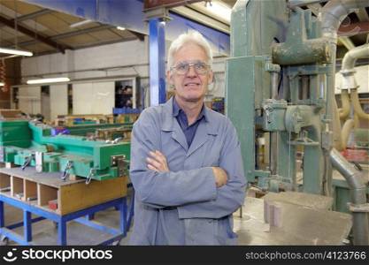 portrait of senior worker on factory floor next to machine