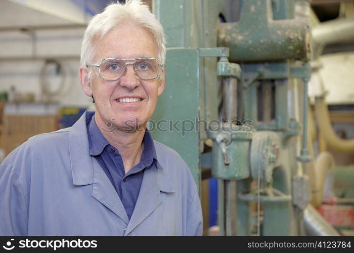 portrait of senior worker on factory floor next to machine