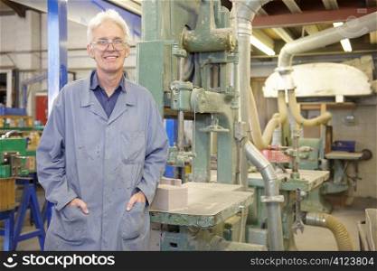 portrait of senior worker on factory floor next to machine